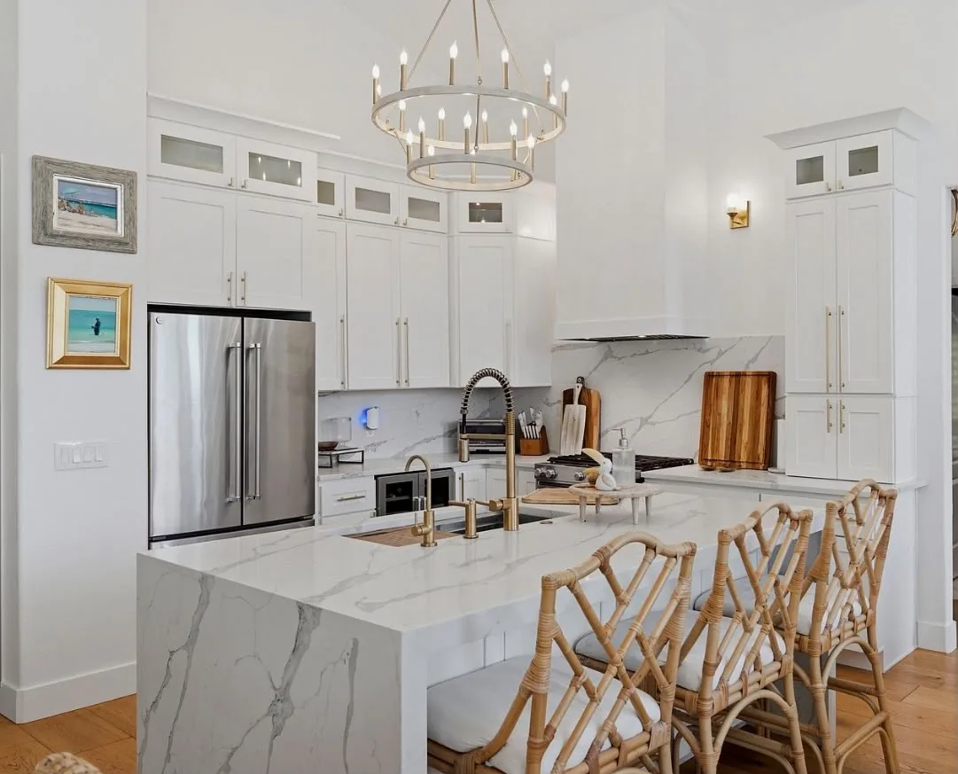 Marble waterfall island with brass faucets and rattan counter stools