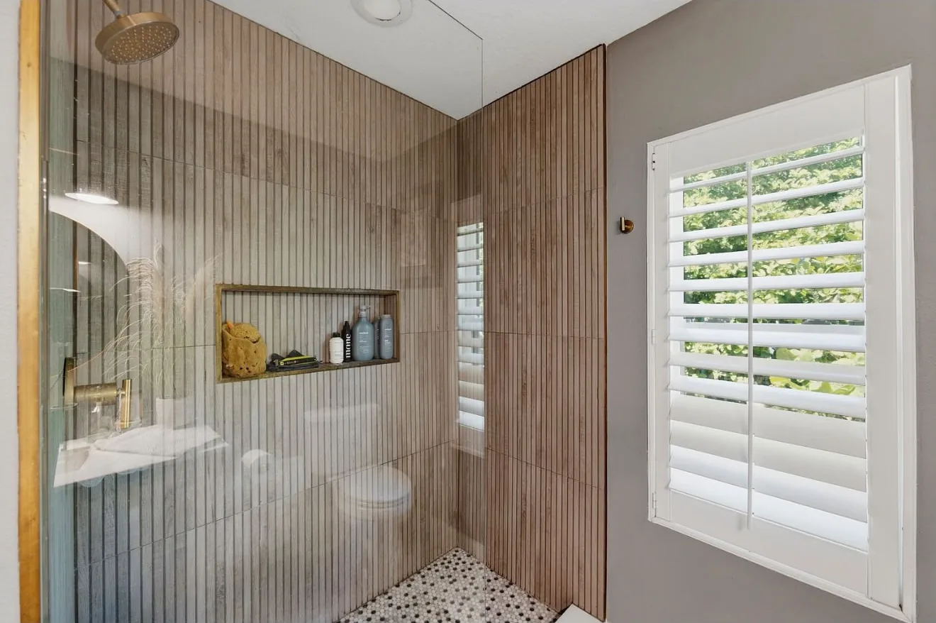 Walk-in shower with fluted wood-look tile and a brass niche