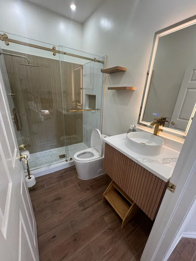 Guest bathroom with a brass-framed glass shower and fluted wood vanity
