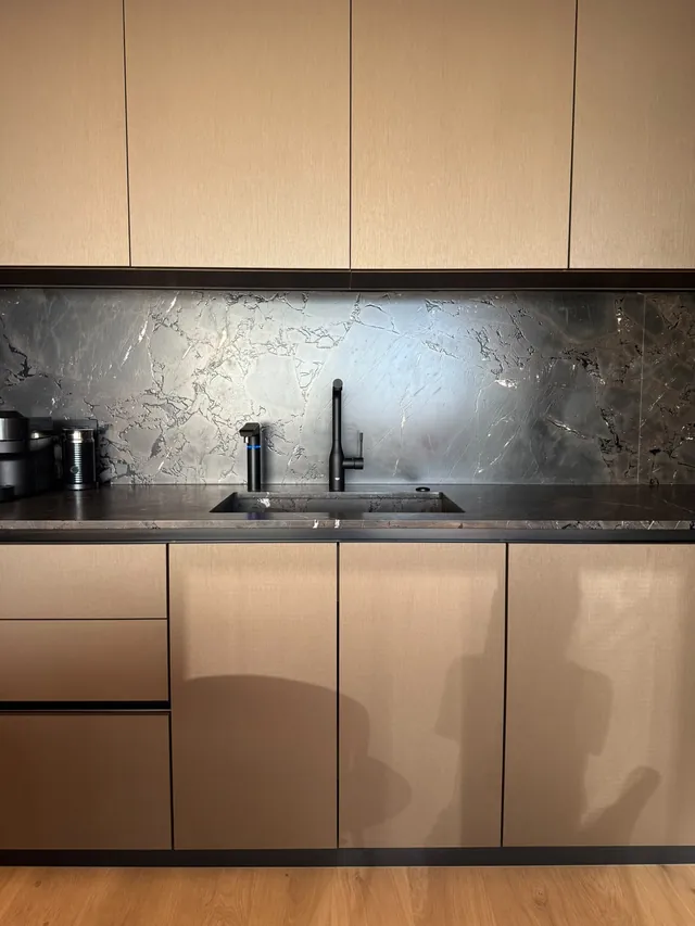 Handleless greige cabinets with a dark stone backsplash
