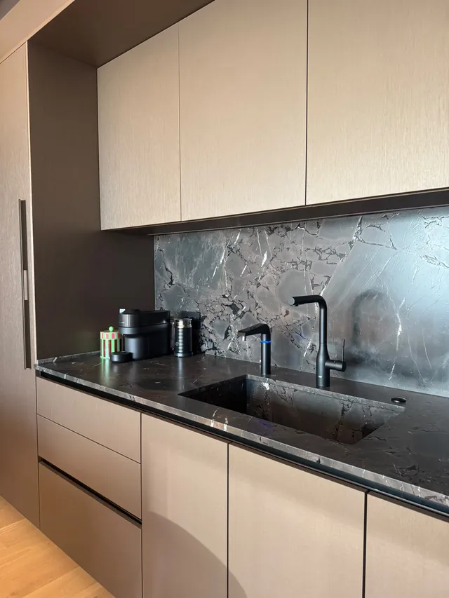 Long kitchen run with dark stone counter and greige cabinets