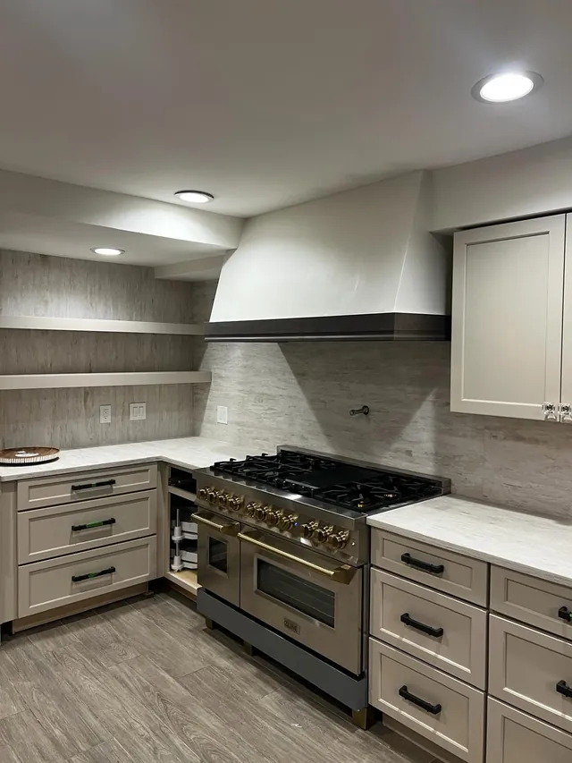 White kitchen with a professional range, floating shelves and gray shaker cabinets